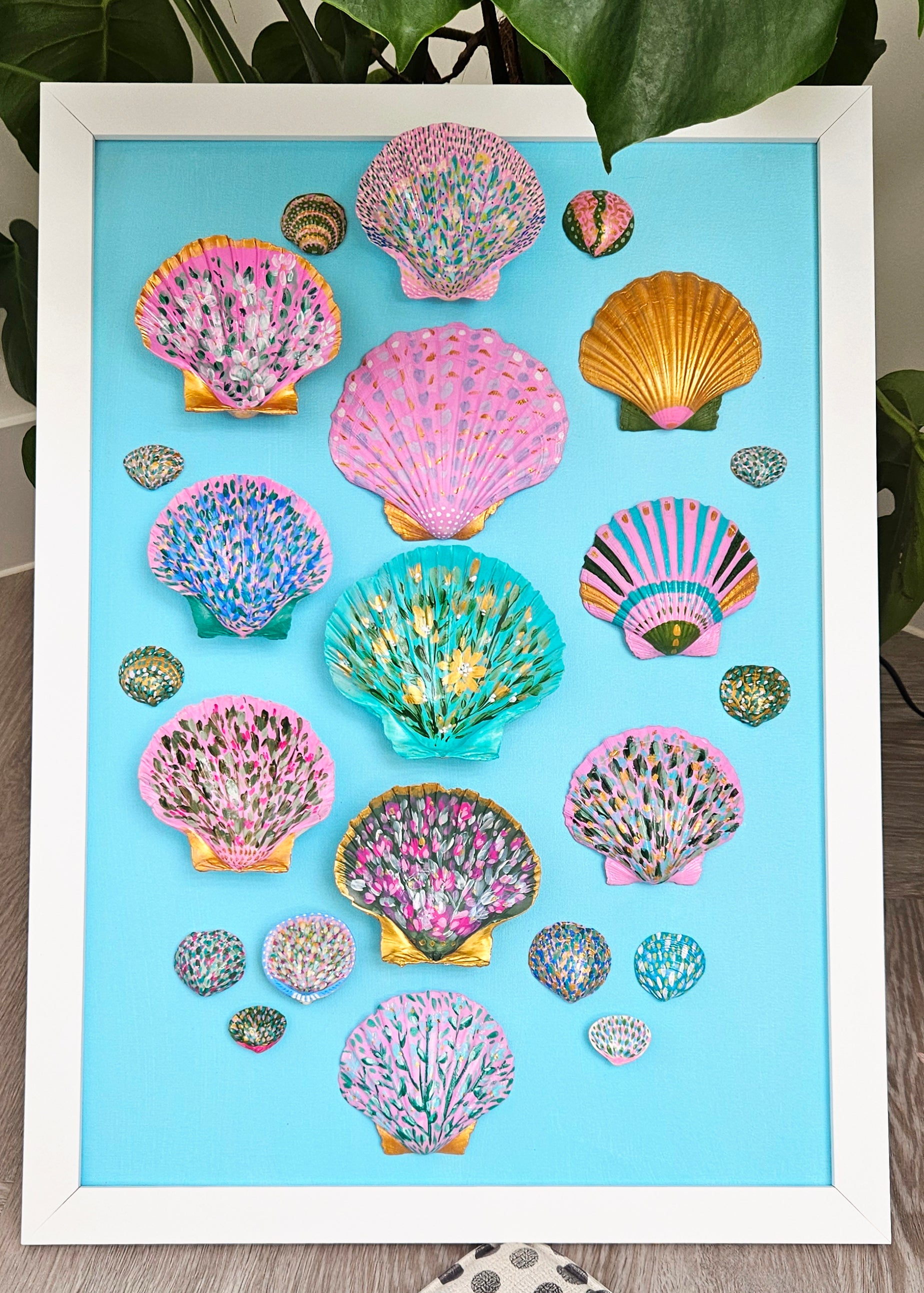 Framed artwork of colourful painted shell designs on a blue background