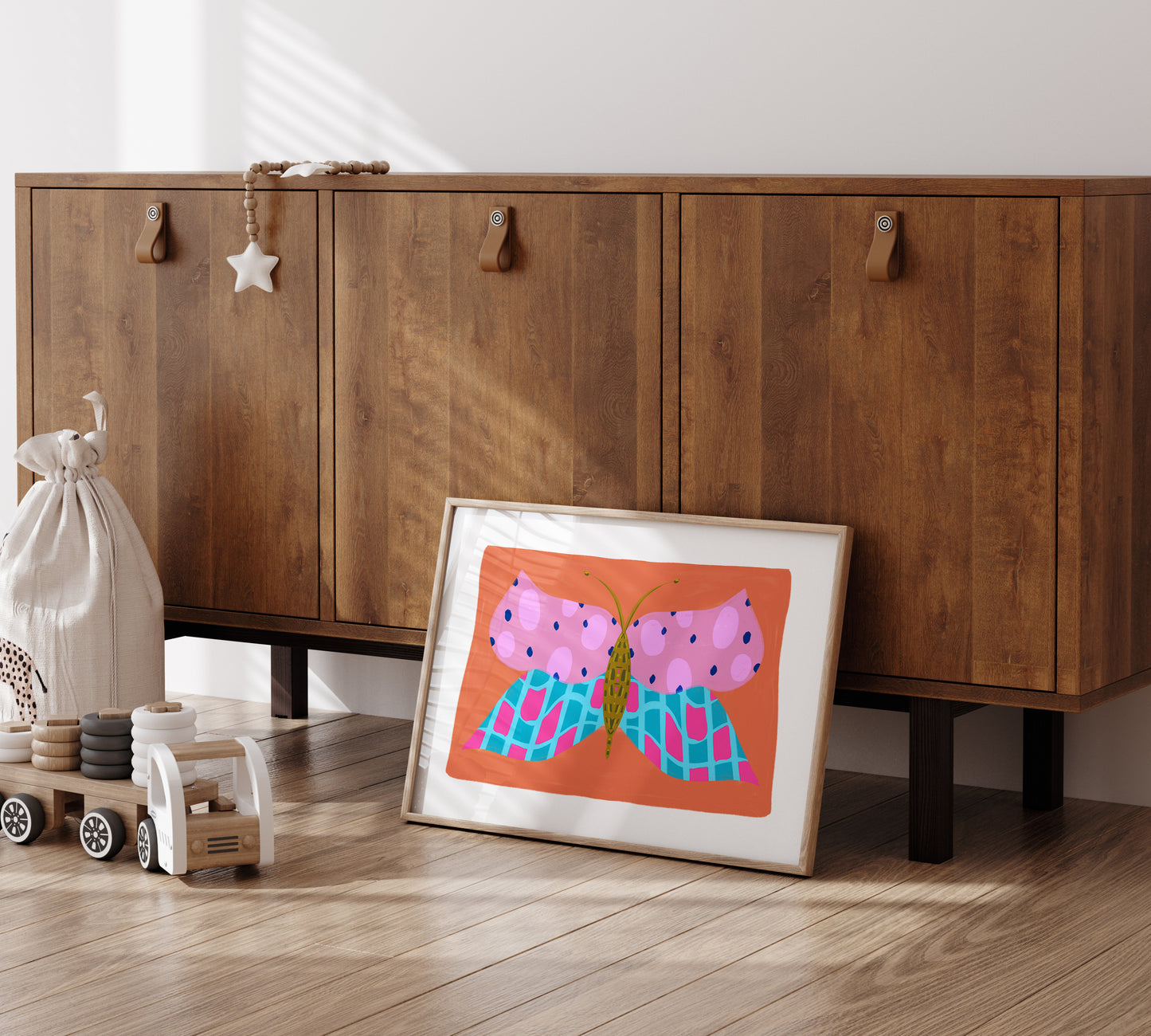 Wooden cabinet with a framed print of a butterfly on a wooden floor.