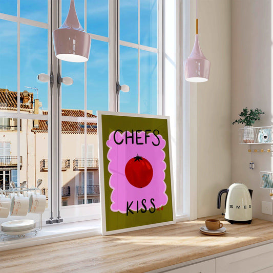 Bright kitchen nook wall art print featuring a painted red tomato with "chefs kiss" handwritten. On a green and pink textured background.