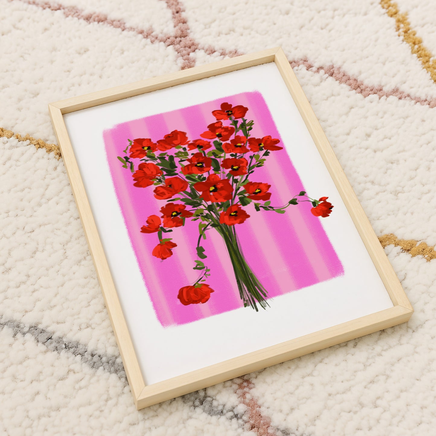 Framed artwork of red flowers on a pink background on a textured carpet surface