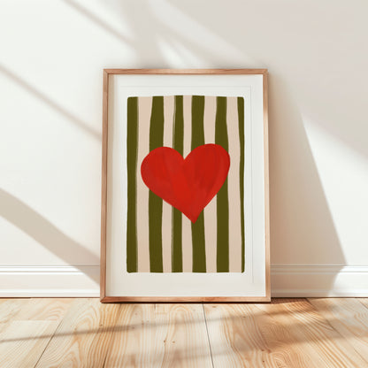 Framed artwork with a red heart on a striped background on a wooden floor.