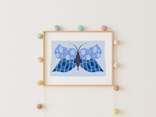 Framed artwork of a blue butterfly on a white wall with decorative pom-poms.