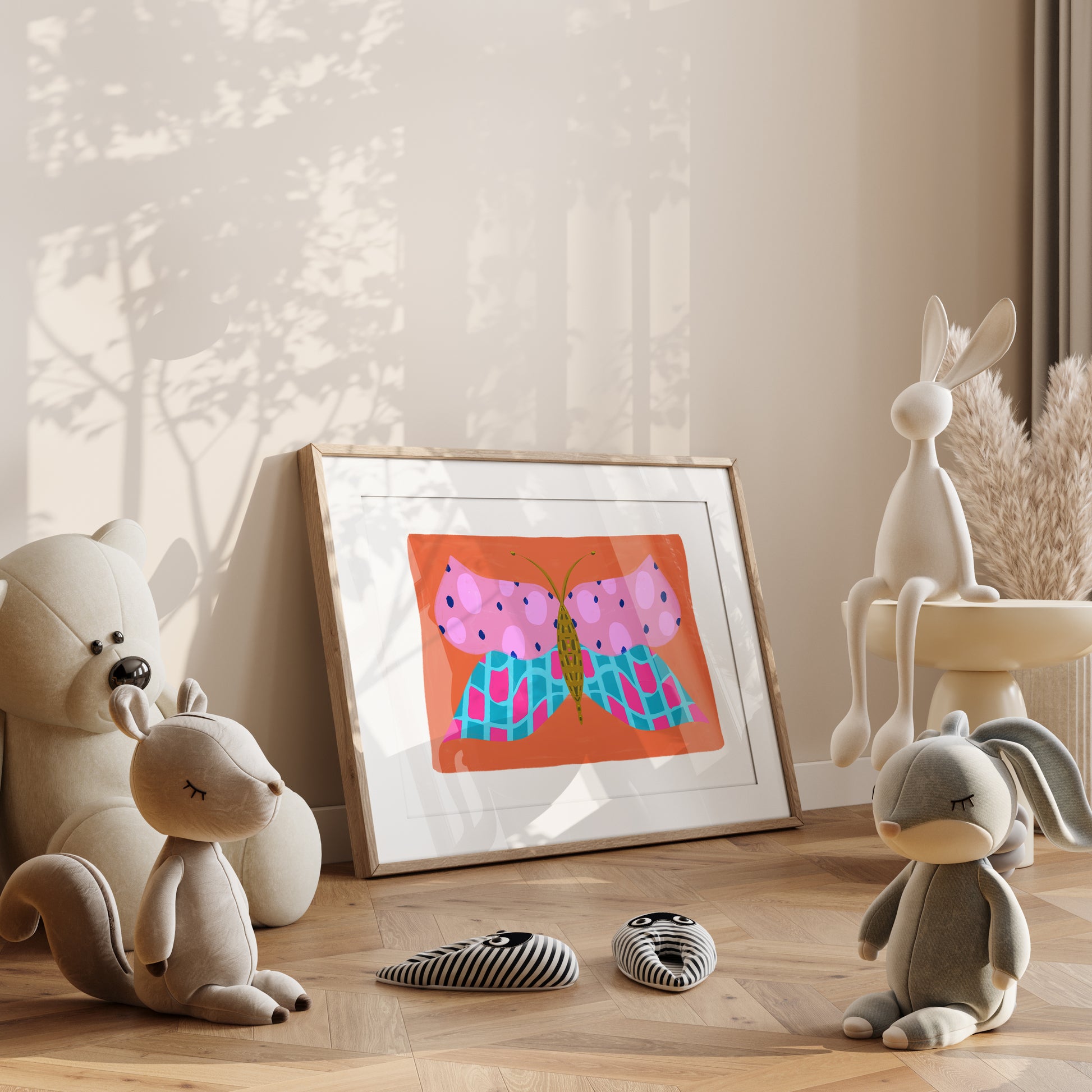 Framed children's artwork of a pink and blue butterfly on a shelf with toys and decorative items.