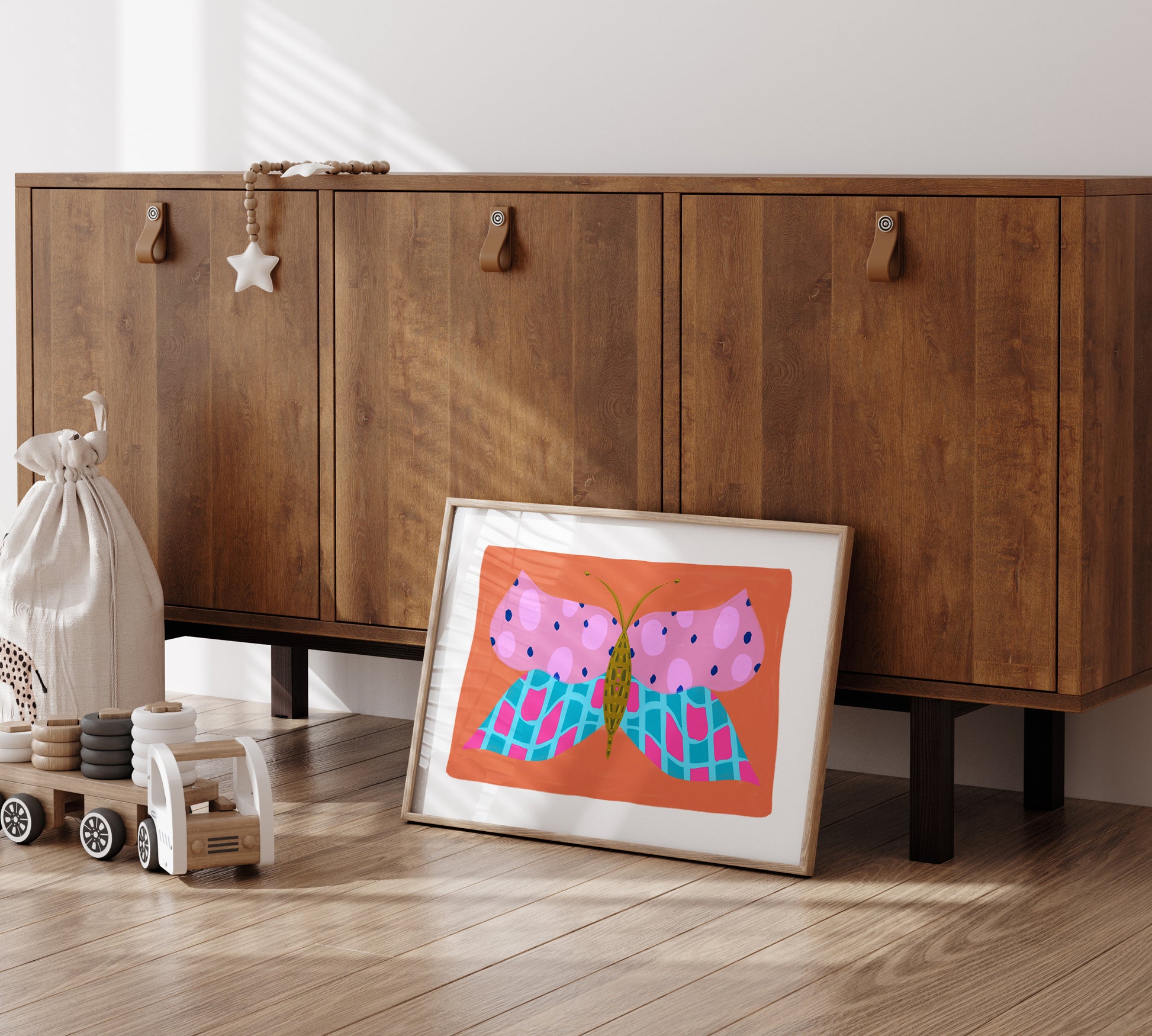 Wooden cabinet with a framed print of a butterfly on a wooden floor.
