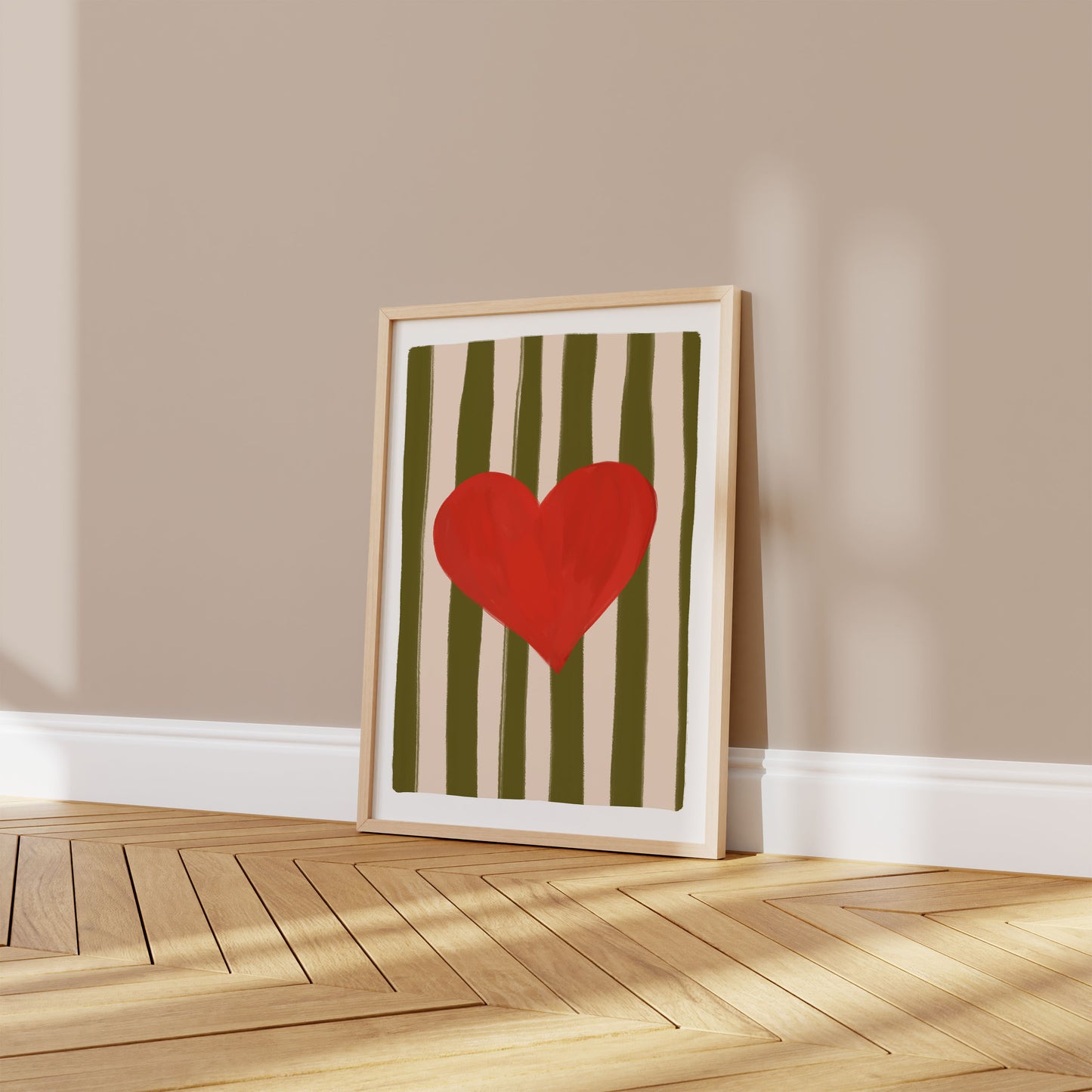 Framed artwork with a red heart on a striped background on a beige wall.