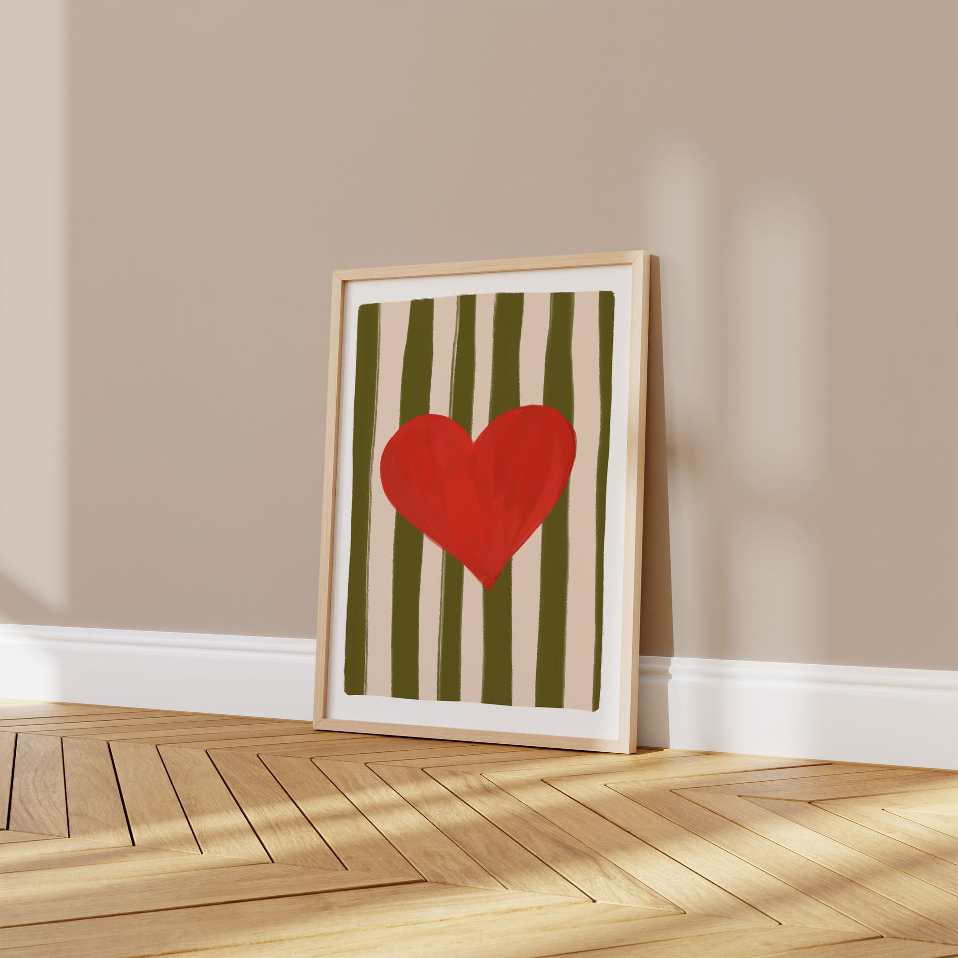 Framed artwork with a red heart on a striped background on a beige wall.