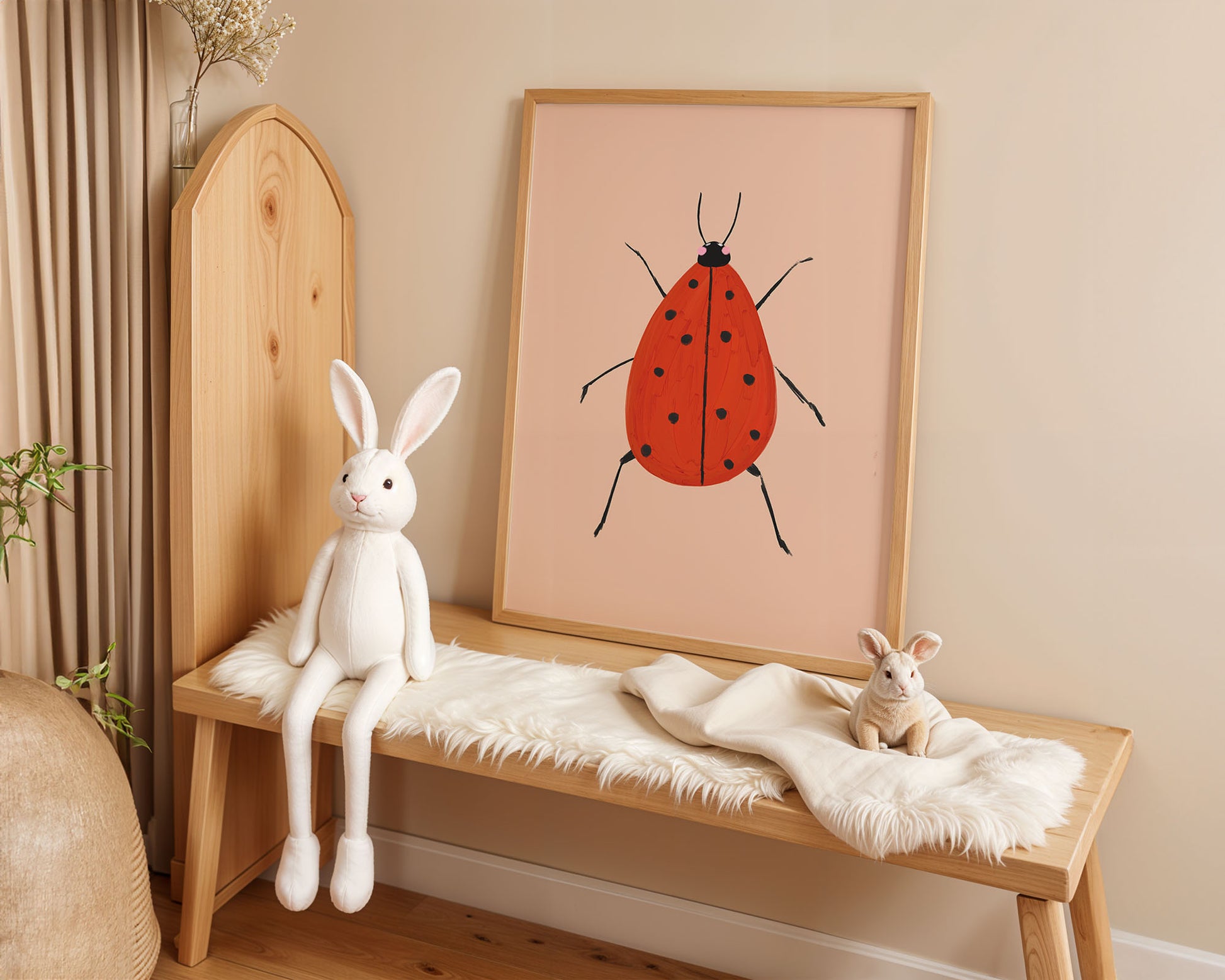 Wooden bench with plush toys and a framed illustration of a red ladybug on a beige wall.