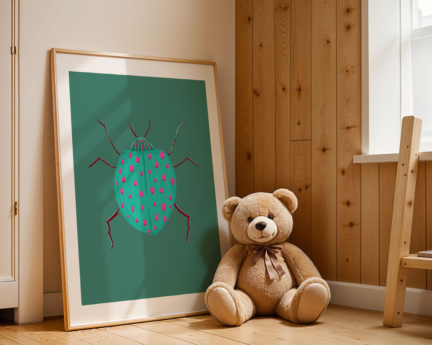 Teddy bear sitting next to a framed illustration of a beetle on a wooden floor.