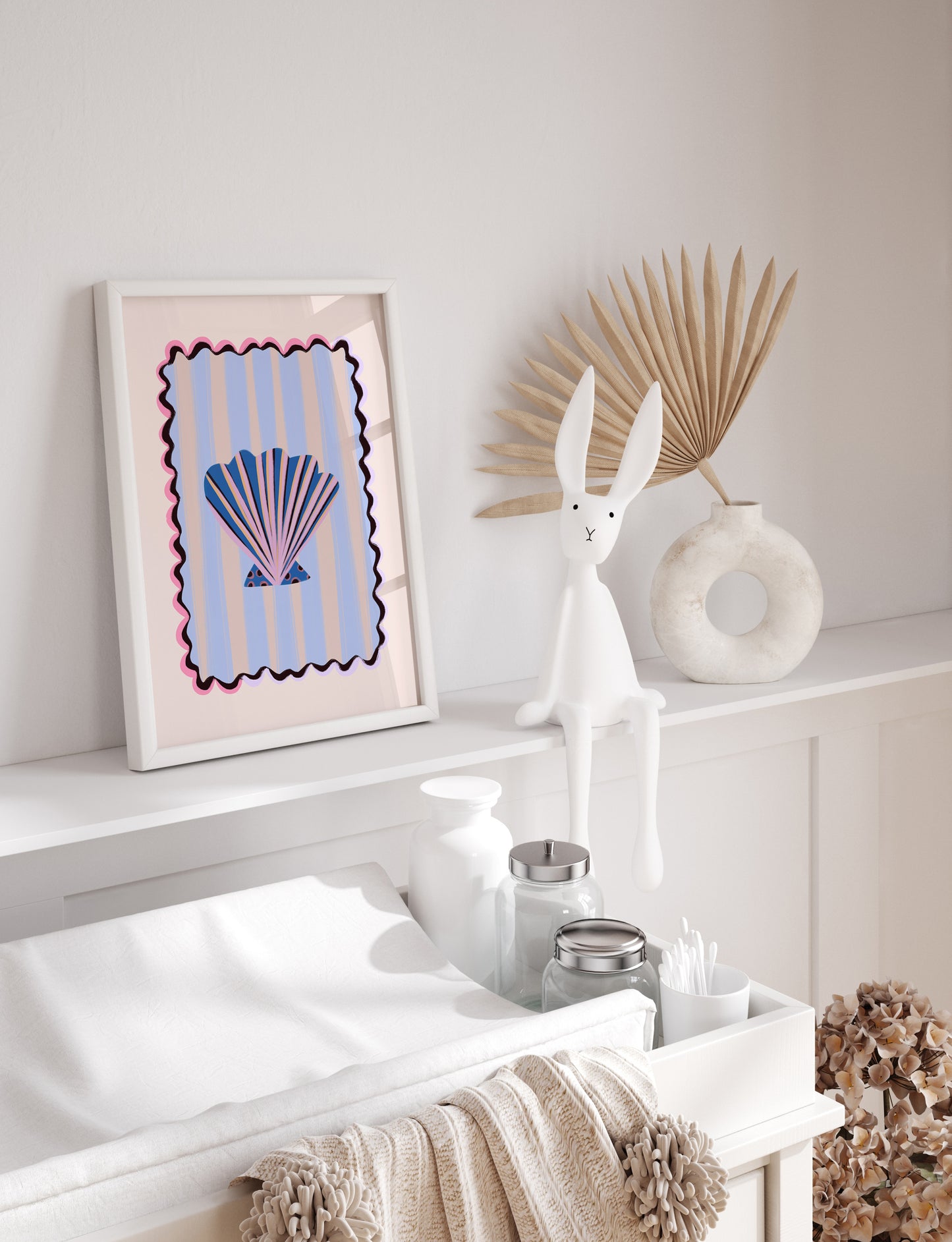 Decorative shelf with a framed shell artwork, rabbit sculpture, and decorative items against a white wall.