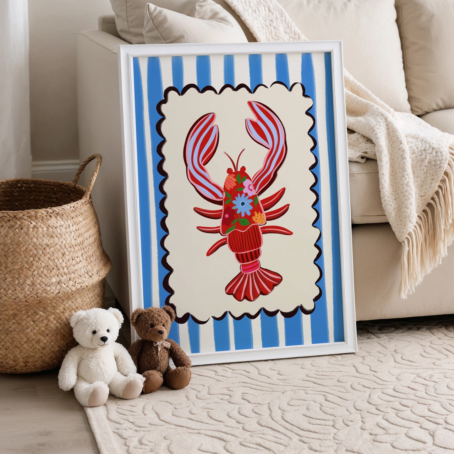 Framed artwork of a red lobster with blue stripes on a white surface, surrounded by teddy bears and a woven basket.