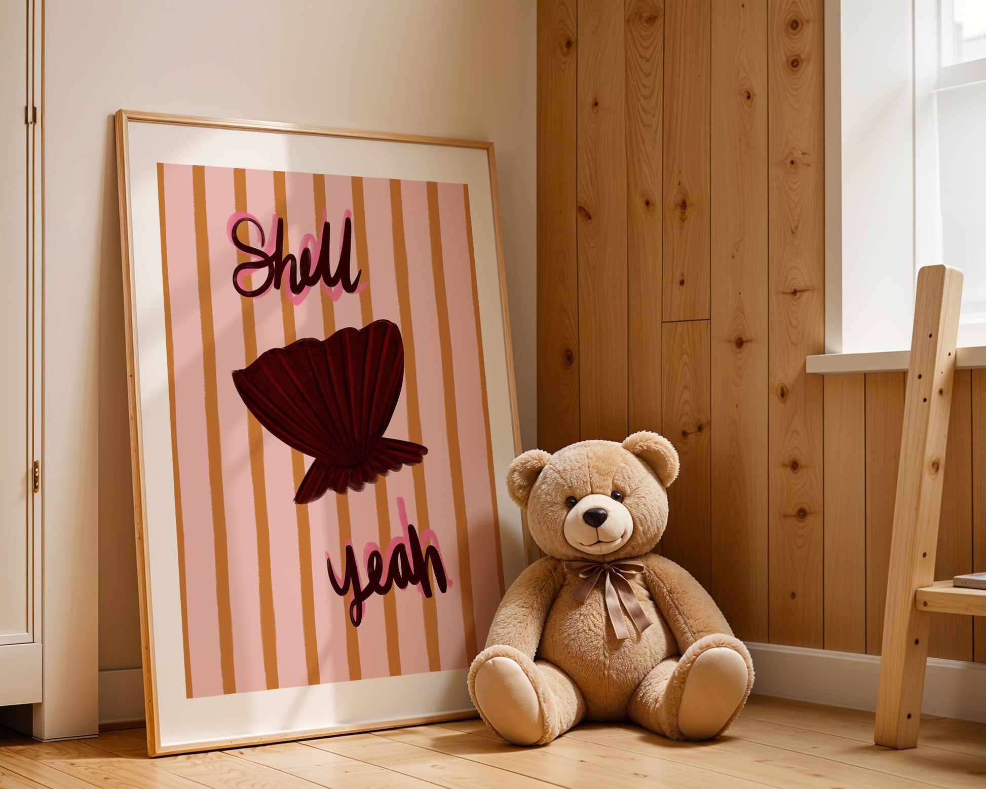 Teddy bear sitting next to a framed picture with a red shell design on a wooden floor.